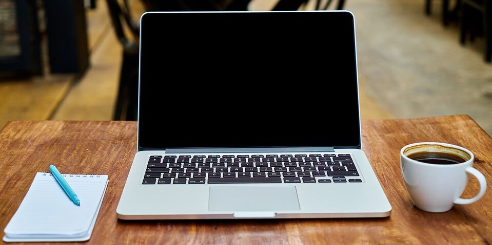 Laptop mit Notizblock und Kaffee